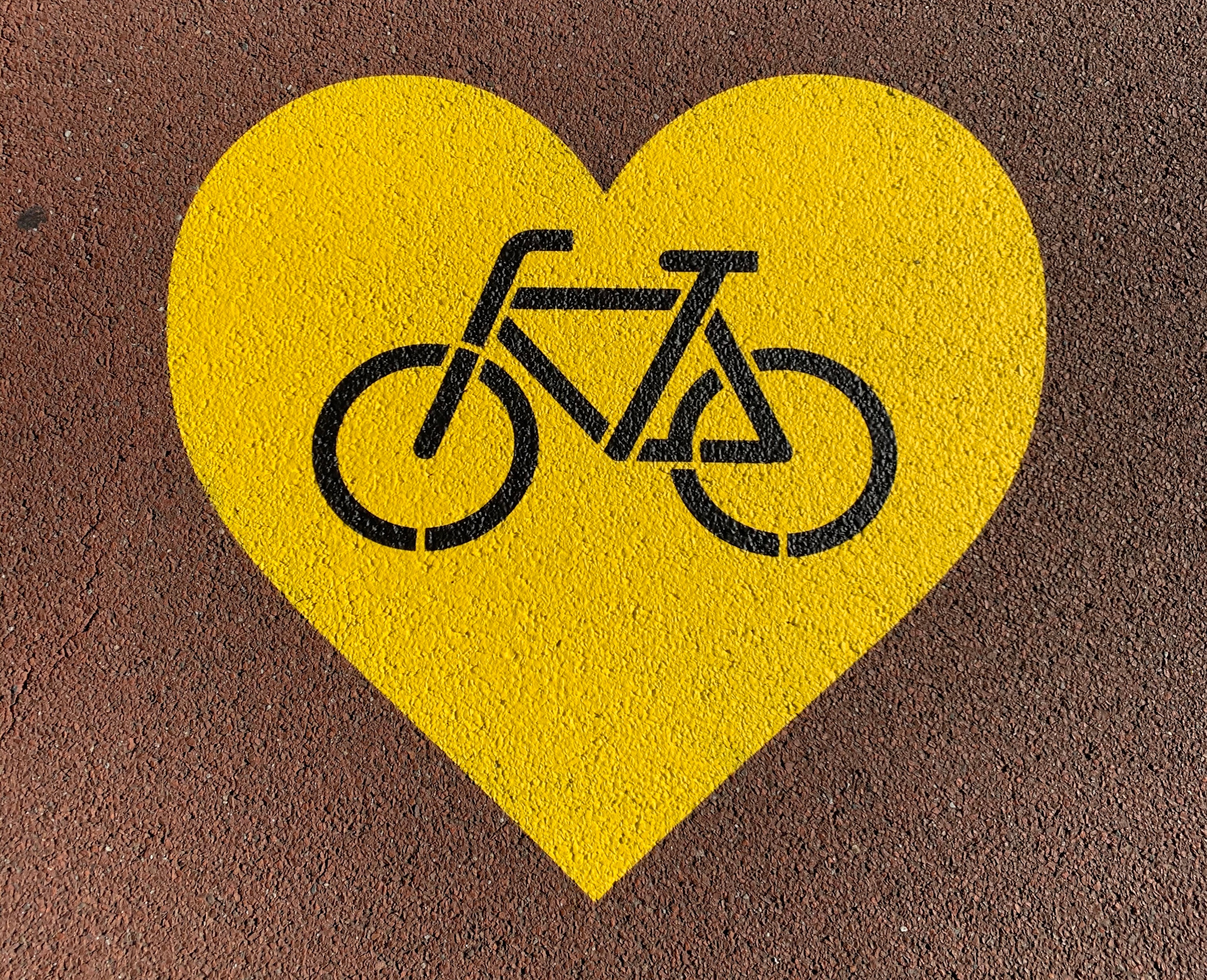 A yellow painted stencil in a heart shape with a bicycle in the middle