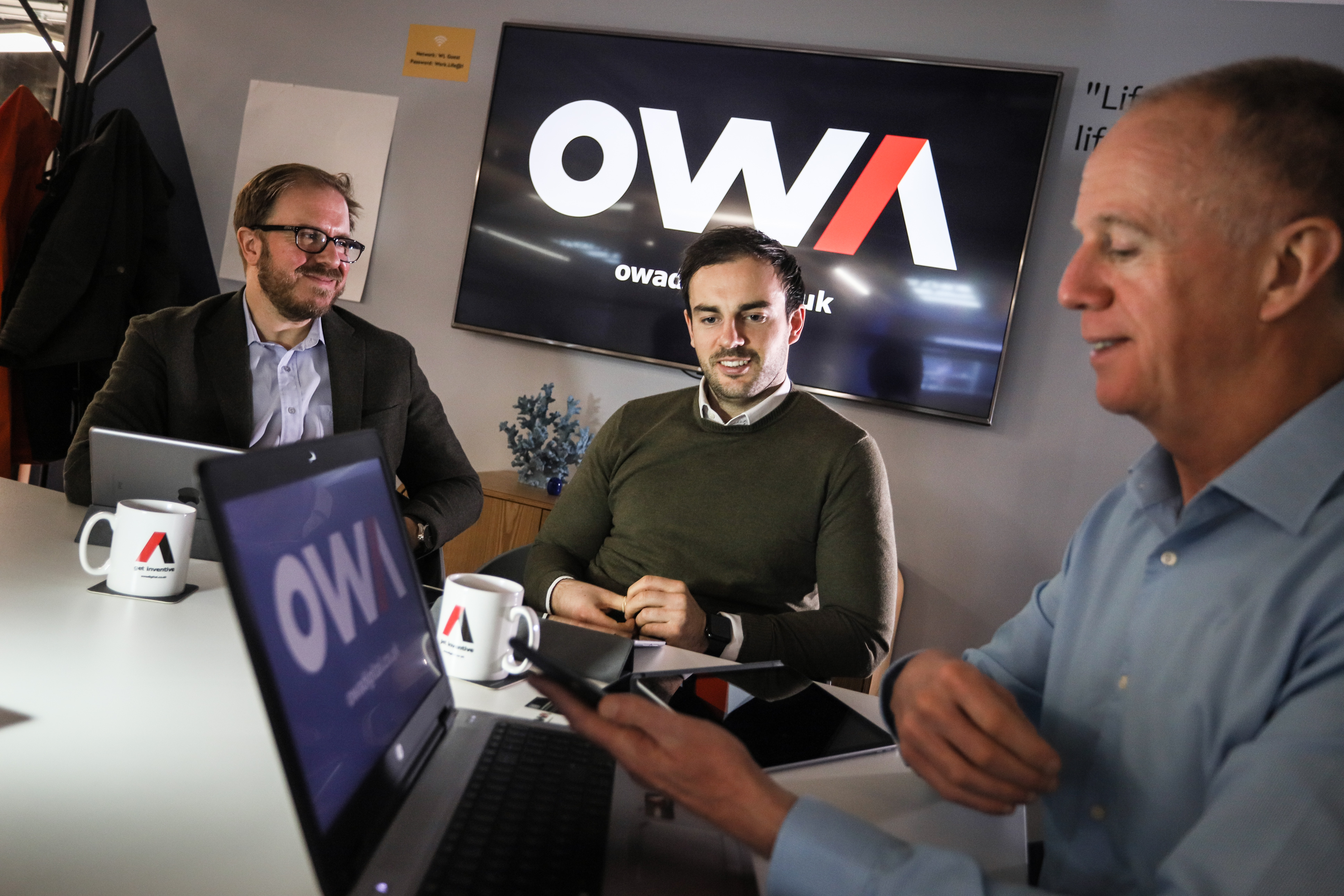 Three individuals looking at a laptop.