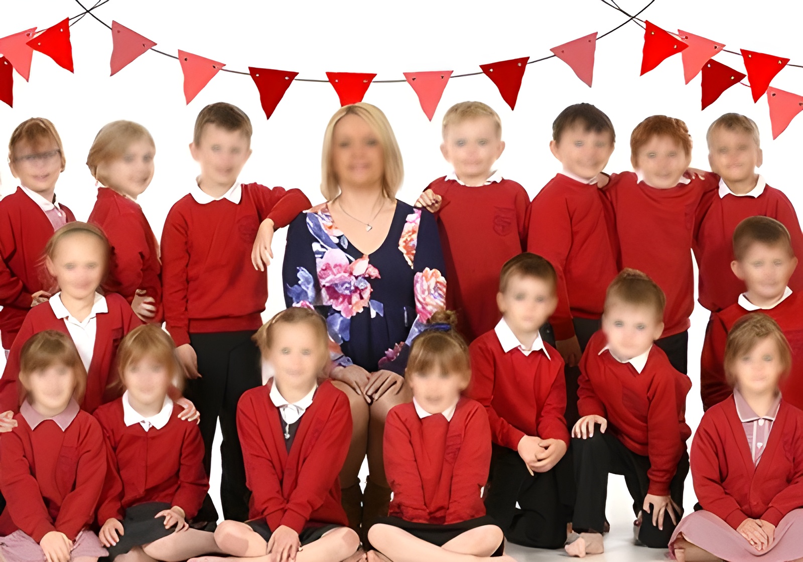A group of children wearing red school uniforms, smiling and standing together in a playground setting.