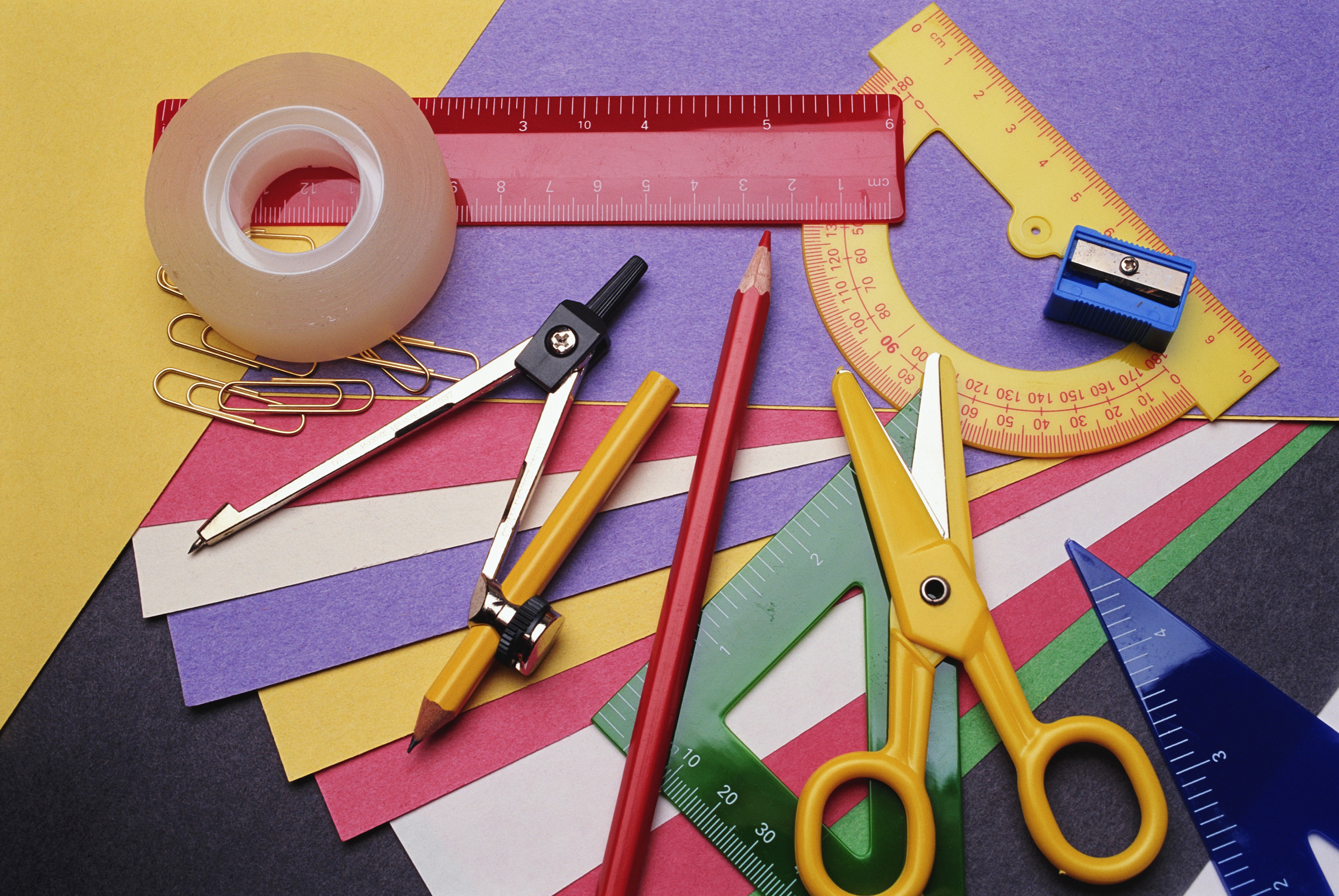 A variety of school supplies, including notebooks, pens, and pencils, neatly arranged on a wooden table.