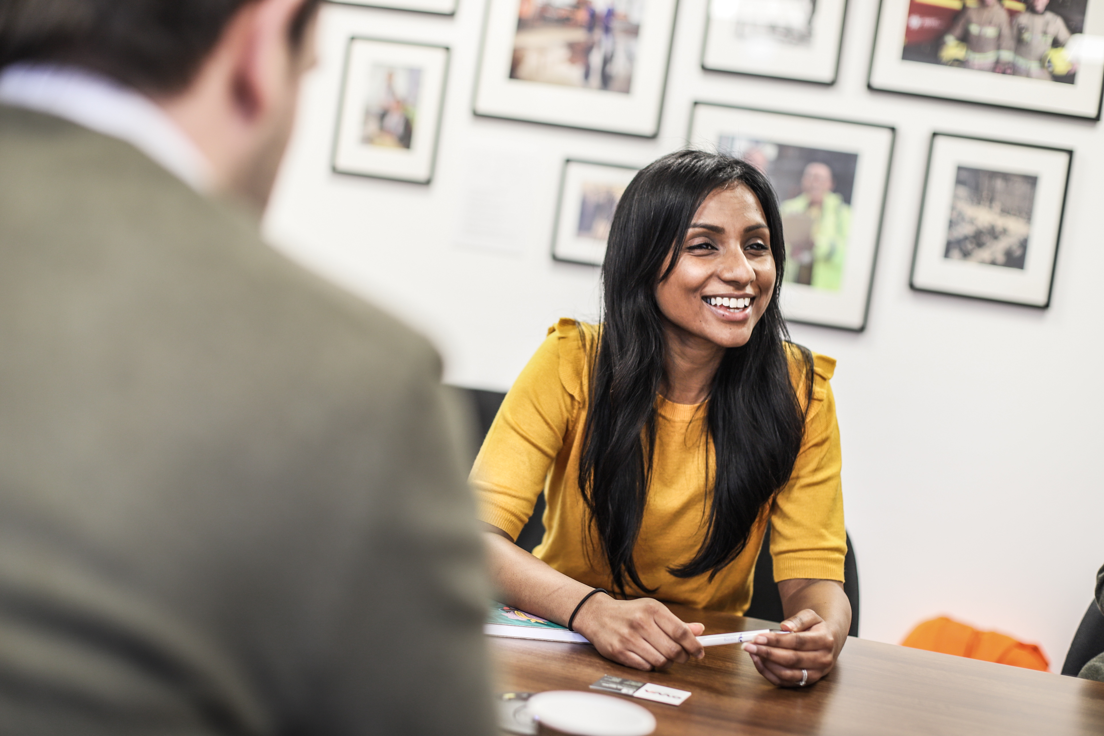 A smiling client sits at a table with two OWA team members, discussing legacy system support in a collaborative setting