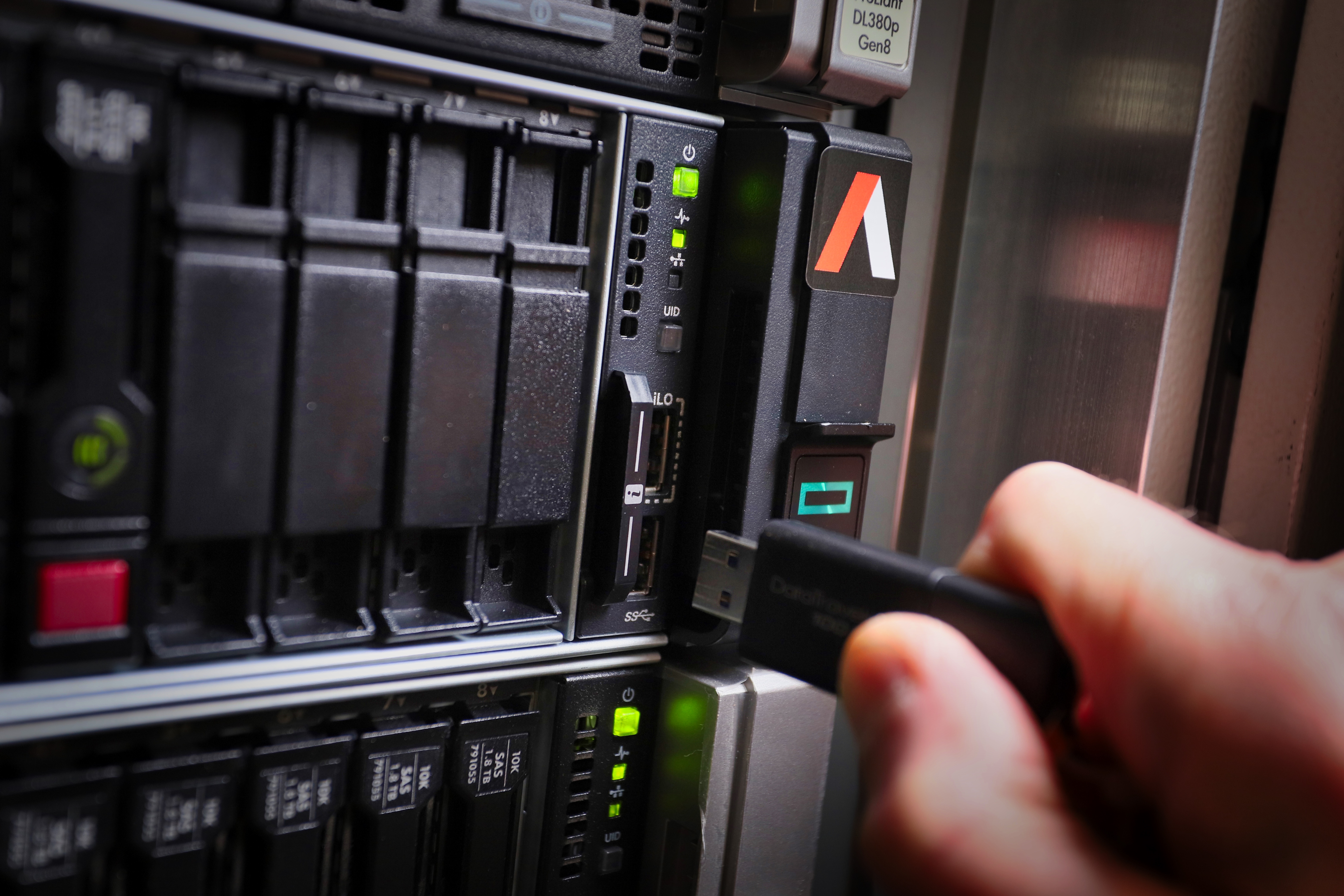 An OWA team member holding a USB stick in front of a server, highlighting the importance of legacy system support