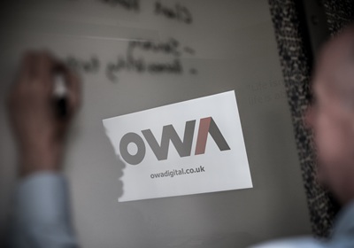 An OWA team member writing on a board in an office space designed for innovation, while providing essential legacy system support for clients