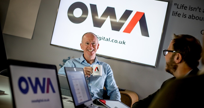 Two OWA team members in an office discussing Web Application Development while looking at a tablet together.