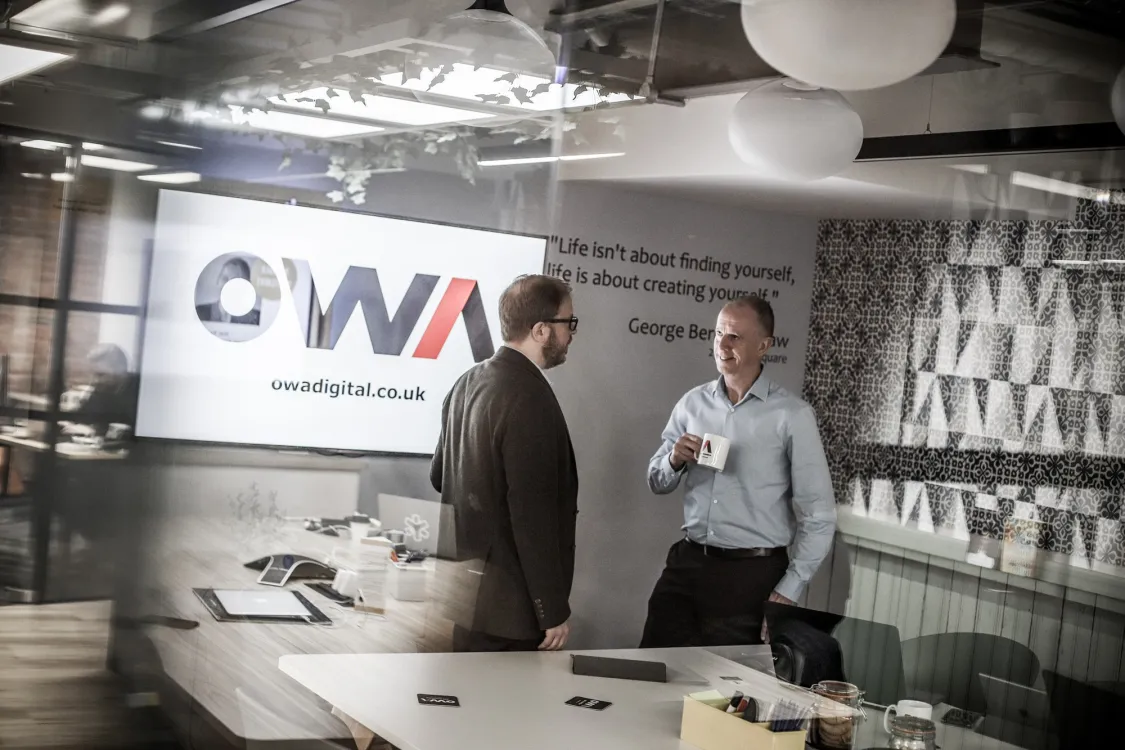 Two OWA team members talking in a modern office.