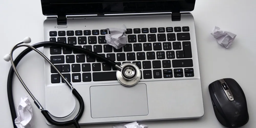 A laptop with a stethoscope on top, symbolizing Web Application Development in the healthcare sector