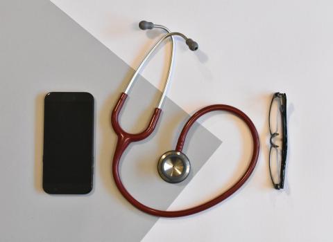 Smartphone next to a stethoscope and glasses