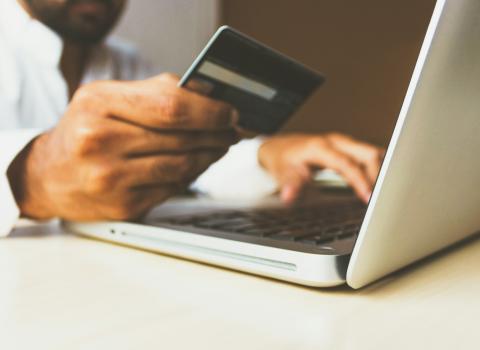 Man on laptop holding credit card