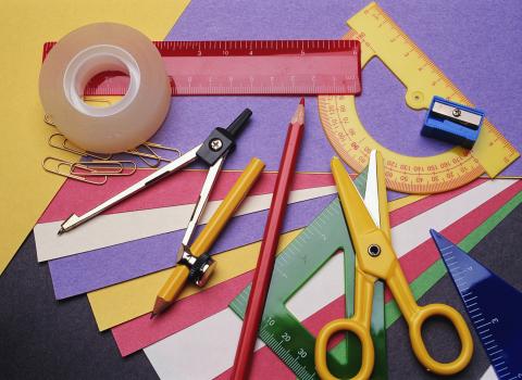 A variety of school supplies, including notebooks, pens, and pencils, neatly arranged on a wooden table.