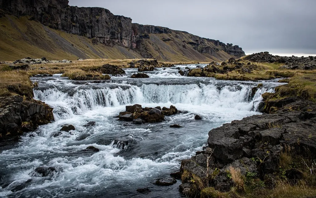 A scenic waterfall in Iceland surrounded by rocks and lush green grass, showcasing the natural beauty of the landscape.