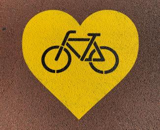 A yellow painted stencil in a heart shape with a bicycle in the middle