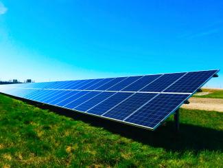 An array of solar panels in a field showing renewable energy generation for greater sustainability